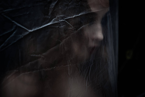 Young beauty sad woman trapped behind a plastic sheet as protection against COVID-19. Nicely fits for book cover  - Fotoğraf, Görsel
