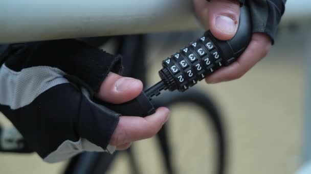 Κοντινό πλάνο κλειδώματος συνδυασμού για ποδήλατο. Αρσενικά χέρια το κλείνουν και ανακατεύουν αριθμούς - Πλάνα, βίντεο