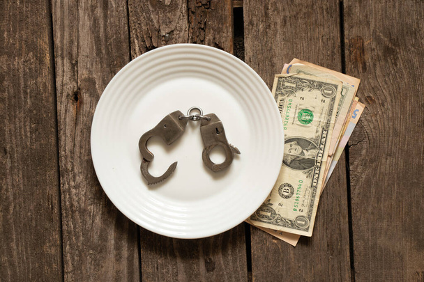 Americké dolary leží na starém dřevěném stole vedle pout, financí a korupce - Fotografie, Obrázek