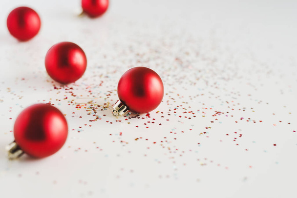 Background with small red Christmas balls and colorful glitters on white background - 写真・画像