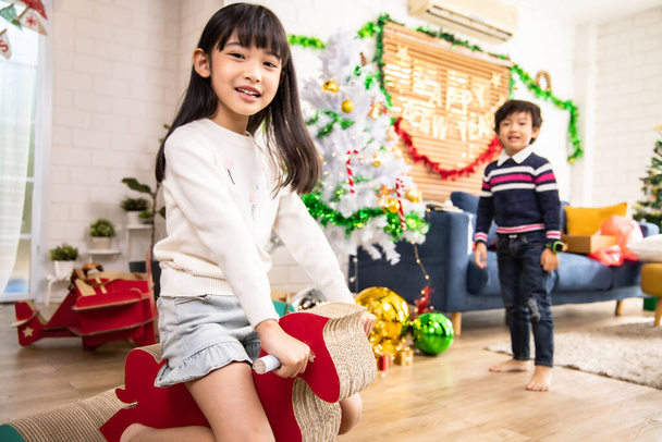 Cute kids playing while parents relaxing at home together, smiling active boy entertaining with paper toy,rocking horse , happy family spending time together in living room on weekend.Asian family happy time concept. - Foto, immagini