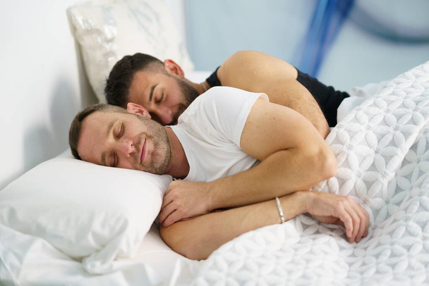 Gay couple sleeping together hugging in bed. - Photo, image