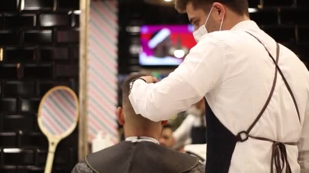 Disparo en el espejo de un peluquero con una pajarita y correas cortando el pelo - Metraje, vídeo