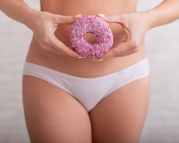 Faceless woman in white panties hold a pink donut - 写真・画像