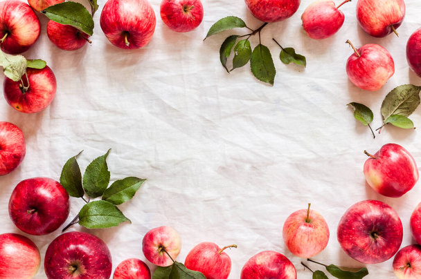 Ripe Red Apples with Leaves, Wrinkled White Cloth Background, copy space for your text - Fotó, kép