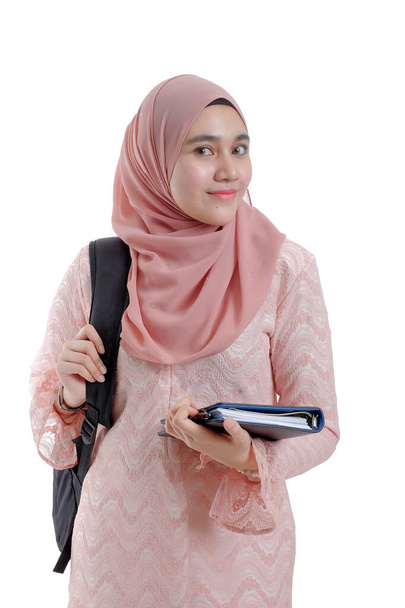 Pěkná moderní asijská žena v hlavě šátek s batohem úsměv a držení knihy. - Fotografie, Obrázek