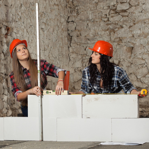 dwie młode kobiety długowłosy zbudowany nowy ściany z bloków - Zdjęcie, obraz