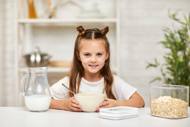 little girl eating breakfast: cereal with the milk in the kitchen. - Foto, Imagem