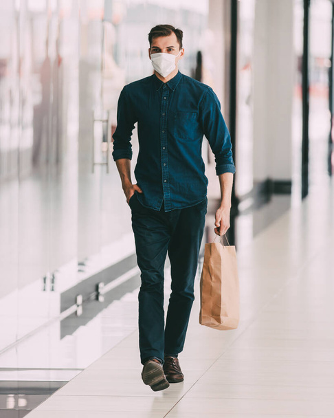 man in a protective mask passing near a supermarket. - Foto, Bild