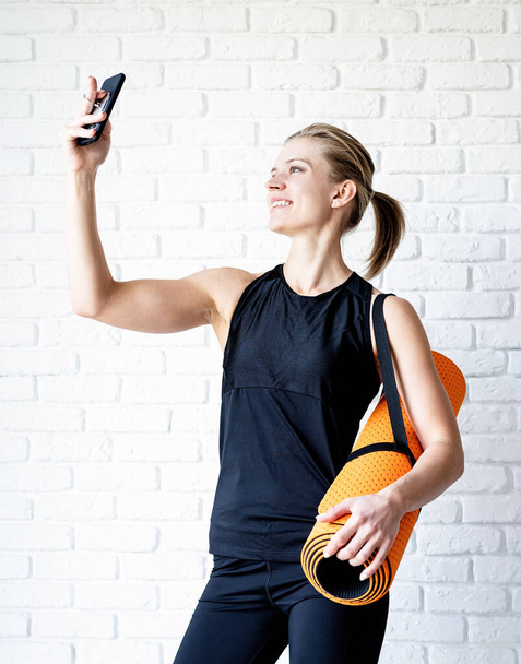 Sağlıklı bir yaşam tarzı. Spor ve spor. Genç gülümseyen fitness kadını antrenmandan sonra selfie çekiyor. - Fotoğraf, Görsel