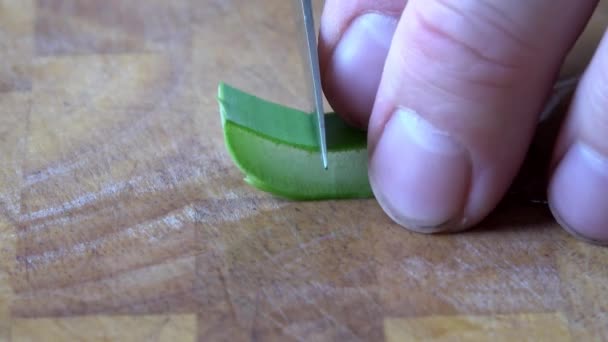 Aloe vera est coupé en petits morceaux sur une planche de bois - Séquence, vidéo