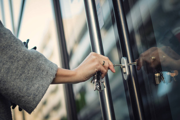 Detailní záběr ženy odemykající vstupní dveře klíčem. Osoba používající klíč a zamykání dveří bytu. - Fotografie, Obrázek