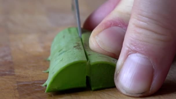 Aloë vera wordt in kleine stukjes gesneden op een houten plank - Video