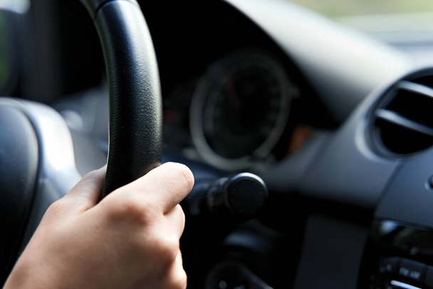 Female hand on steering wheel of a car while driving. Black interior. - Photo, Image