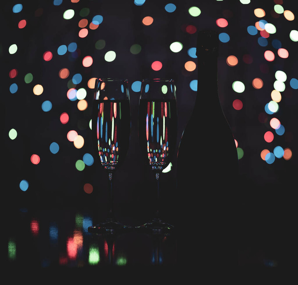 a dark bottle of wine on a beautiful festive bokeh background, composed of colored out of focus lights on a dark background - Foto, imagen