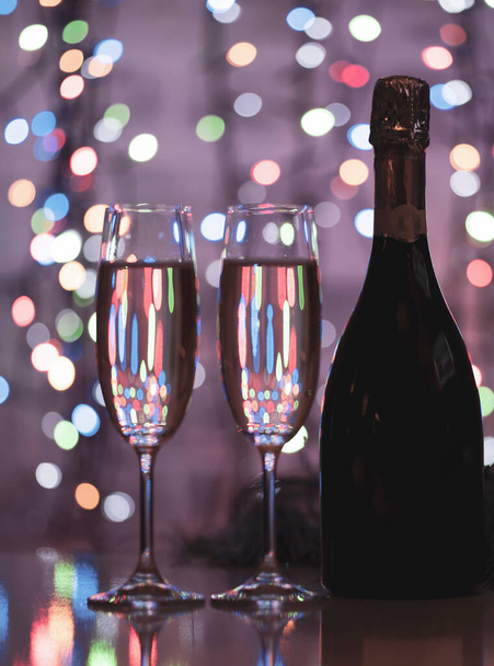 темная бутылка вина на красивом праздничном боке, состоящий из цветных вне фокуса огней на темном фоне - Фото, изображение