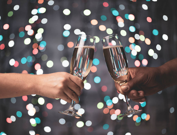 egy lány és egy srác párzanak egy pohár pezsgővel egy gyönyörű ünnepi bokeh háttér, amely színes fókusz fények sötét háttér - Fotó, kép