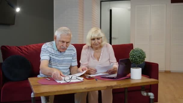 Senior couple checking counting bills bank loan payment doing paperwork discuss unpaid debt taxes - Záběry, video