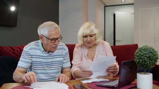 Στρεσαρισμένο ζευγάρι ηλικιωμένων συζητούν απλήρωτα τραπεζικά χρέη κρατώντας λογαριασμούς, κάνοντας χαρτιά, σχεδιάζοντας προϋπολογισμό - Πλάνα, βίντεο