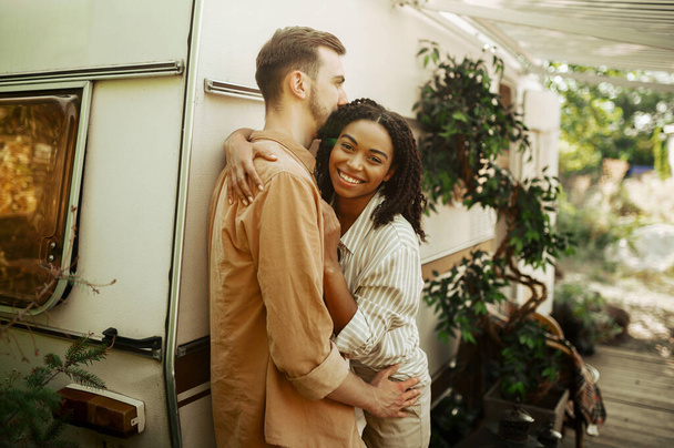 Love couple embraces in rv, camping in a trailer. Man and woman travels on van, romantic vacations on motorhome, campers leisures in camping-car - Photo, image