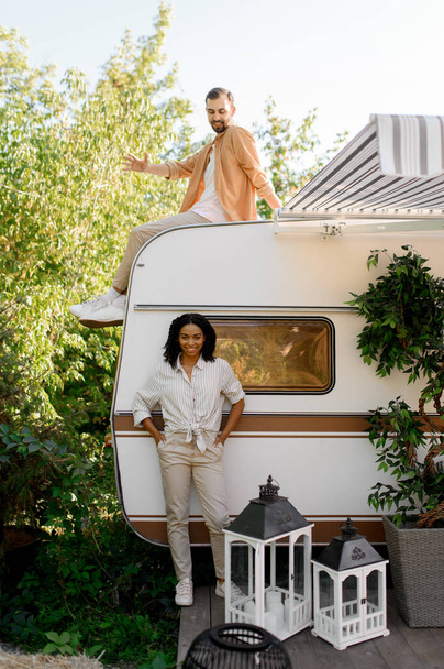 Happy love couple poses near rv, camping in a trailer. Man and woman travels on van, romantic vacations on motorhome, campers leisures in camping-car - Fotoğraf, Görsel