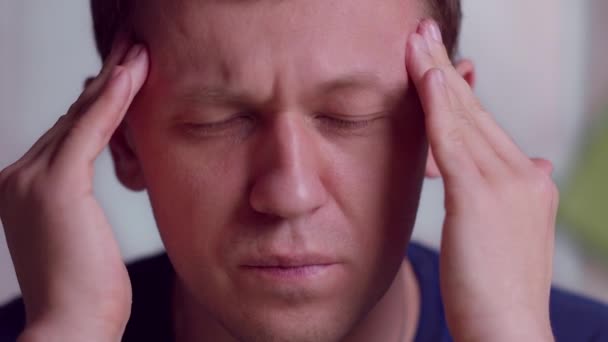 Retrato de un joven con dolor de cabeza severo masajeando sus sienes, primer plano - Metraje, vídeo
