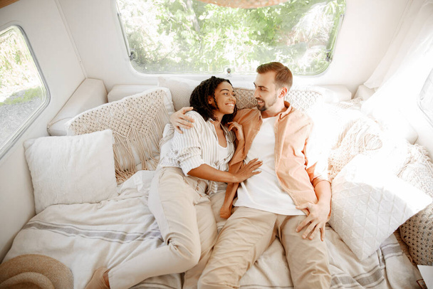 Love couple embraces in rv bed, camping in a trailer. Man and woman travels on van, romantic vacations on motorhome, campers leisures in camping car - Foto, immagini