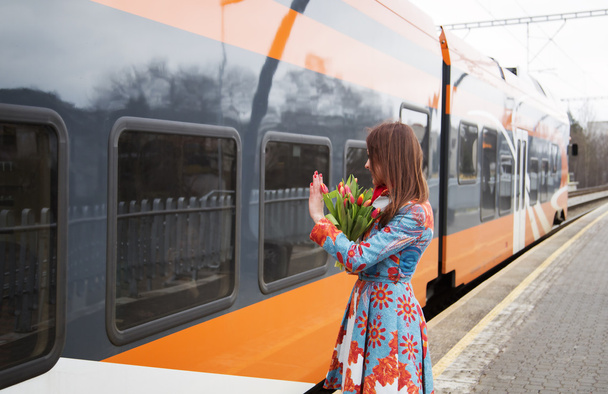 Mulher com flores saudação para treinar passanger
 - Foto, Imagem