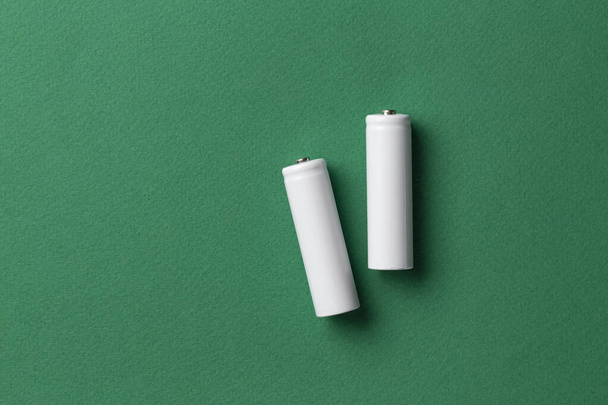 Rechargeable AAA batteries in white on a green background. Place for text. Green energy concept. - Фото, изображение