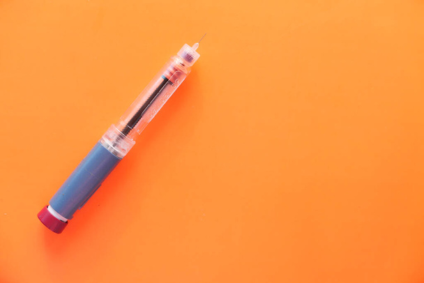 Інсулін ручки на помаранчевому фоні, вид зверху
  - Фото, зображення