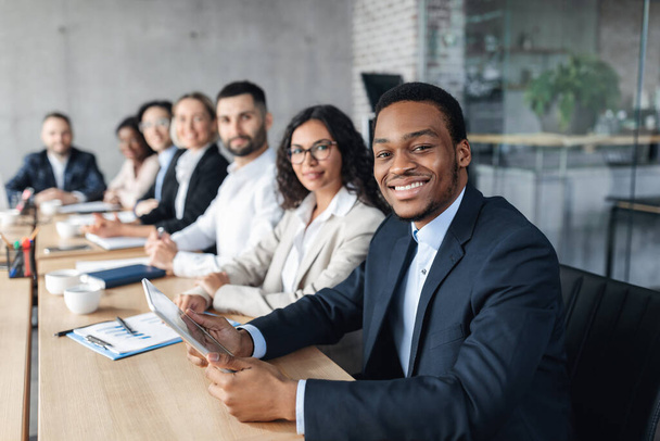Imprenditore africano in riunione aziendale con i colleghi seduti in ufficio - Foto, immagini