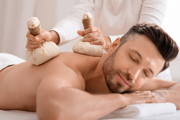 Terapeuta de spa fazendo massagem corporal com bolas de compressa de ervas - Foto, Imagem