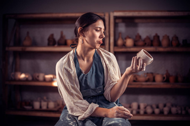 陶器の女の子は、ワークショップで完成した粘土ボウルを示しています。工芸の創造性の概念. - 写真・画像