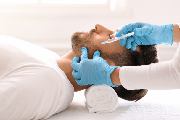 Homme barbu obtenir injection de beauté dans le visage dans le salon de luxe - Photo, image