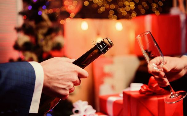 Male hands opening champagne bottle pouring glasses christmas decorations background. Drink champagne or sparkling wine. Celebrate new year with champagne. Toast and cheers concept. Lets celebrate - Fotografie, Obrázek