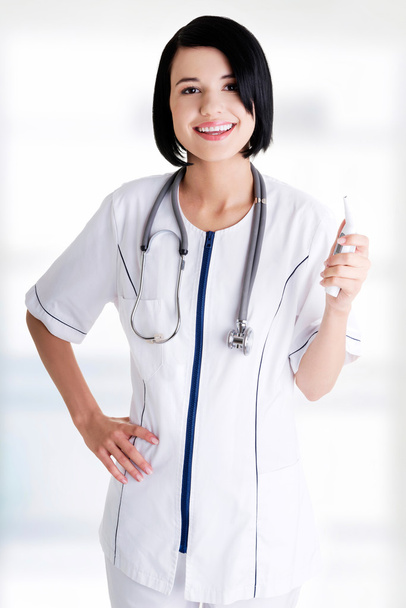 Female doctor or nurse holding digital thermometer - Foto, afbeelding