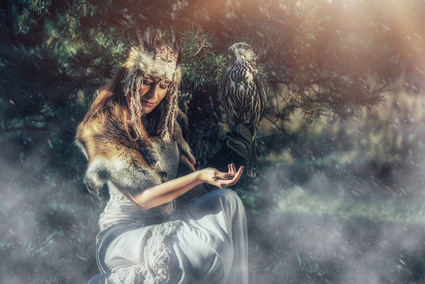 beautiful shamanic woman with falcon in the nature. - Foto, imagen