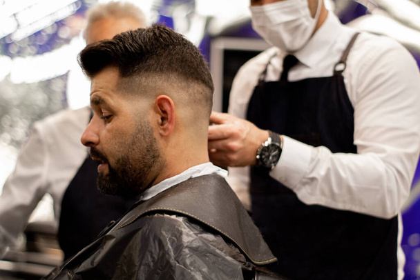 barbeiro jovem com máscara corta o cabelo em um co-trabalho - Foto, Imagem