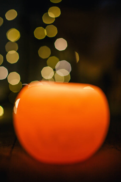 New Years candle burns against the background of the bokeh of the lights of the Christmas garland - Fotoğraf, Görsel