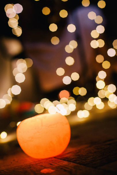 New Years candle burns against the background of the bokeh of the lights of the Christmas garland - Foto, imagen