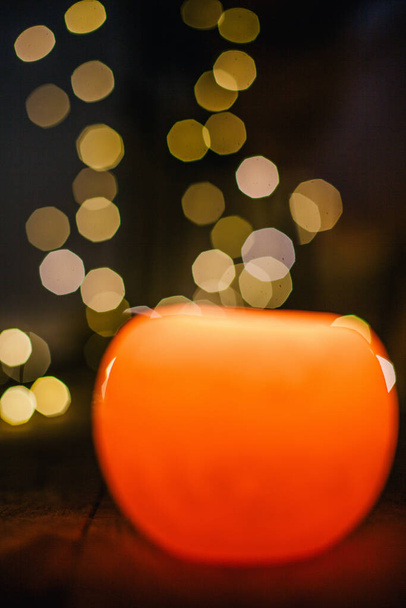 New Years candle burns against the background of the bokeh of the lights of the Christmas garland - Foto, Bild