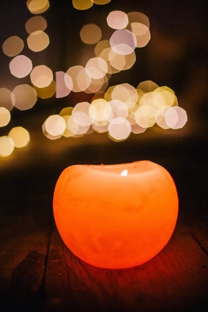 New Years candle burns against the background of the bokeh of the lights of the Christmas garland - Foto, immagini