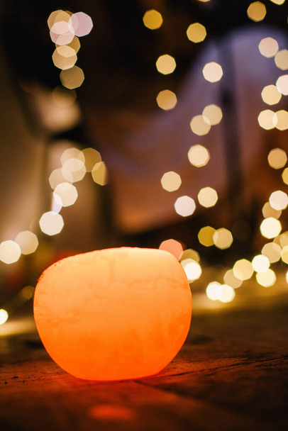 New Years candle burns against the background of the bokeh of the lights of the Christmas garland - Фото, зображення