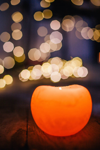 New Years candle burns against the background of the bokeh of the lights of the Christmas garland - Photo, Image