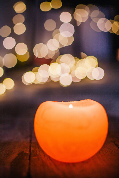 Neujahrskerze brennt vor dem Hintergrund des Bokeh der Lichter der Weihnachtsgirlande - Foto, Bild