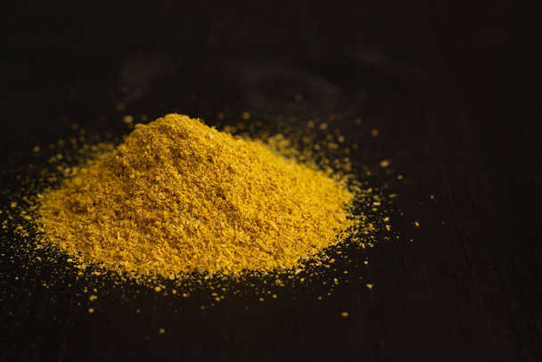 A slide of yellow turmeric or curry spice powder on a black wooden surface, copy space - Zdjęcie, obraz