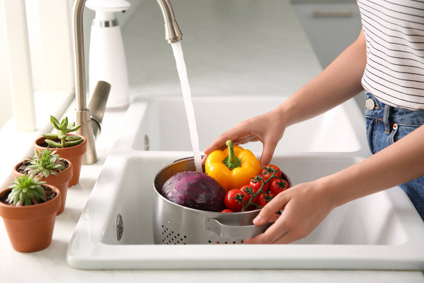 Woman washing fresh vegetables in kitchen sink, closeup - Foto, Imagem