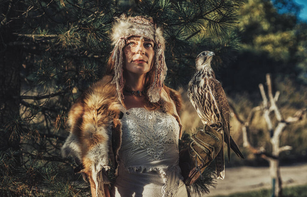 beautiful shamanic woman with eagle in the nature. - Photo, Image