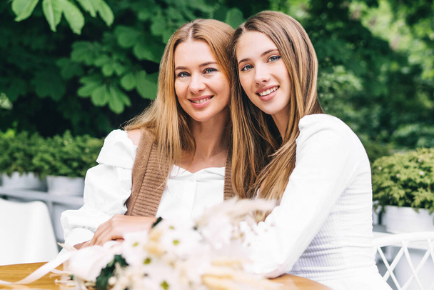 Two smiling blondes mom and daughter look at the camera and smile. - 写真・画像