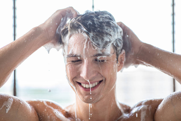 シャンプーで髪を洗うハンサムな若い男性モデル - 写真・画像